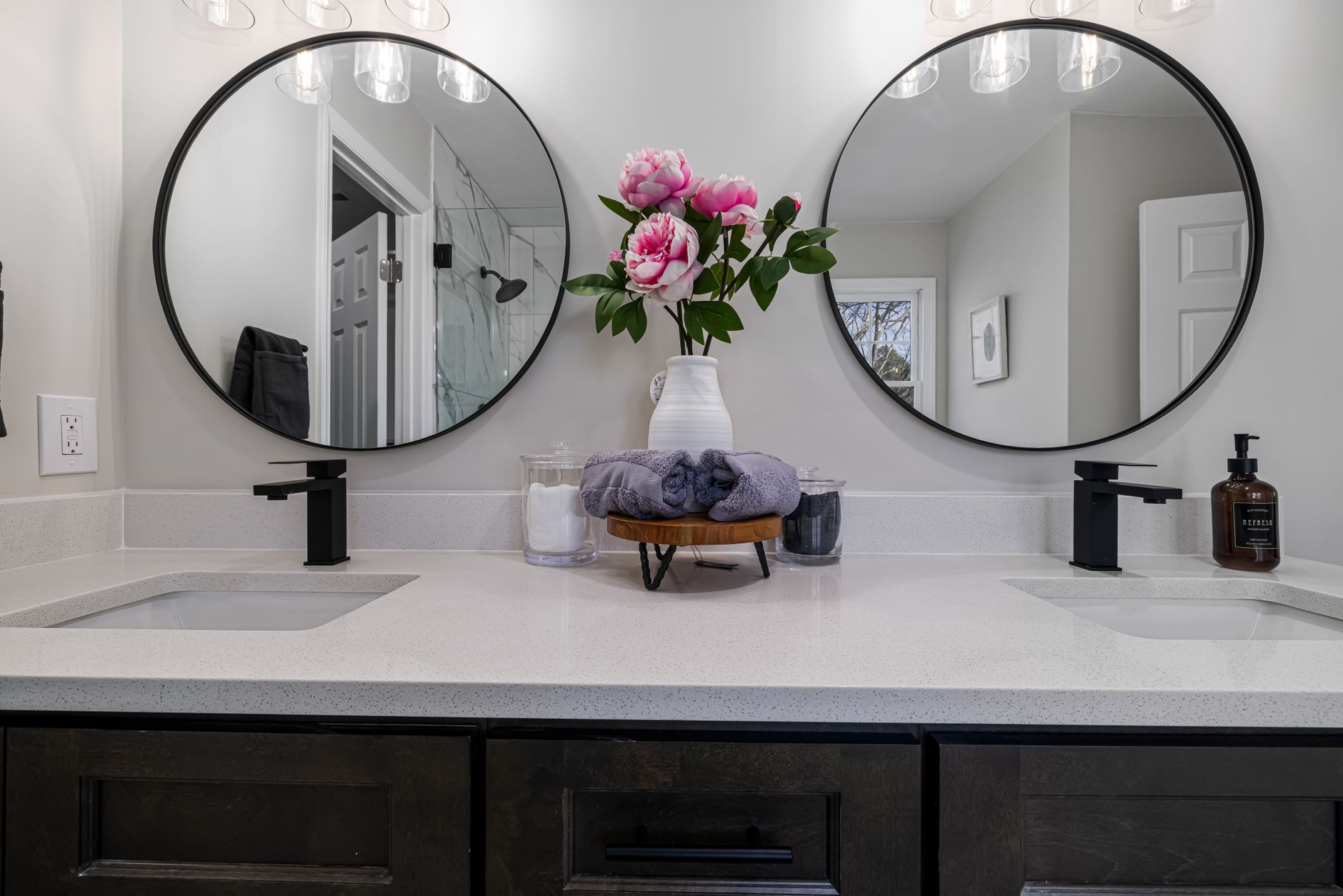 A bathroom vanity with two round mirrors and flowers