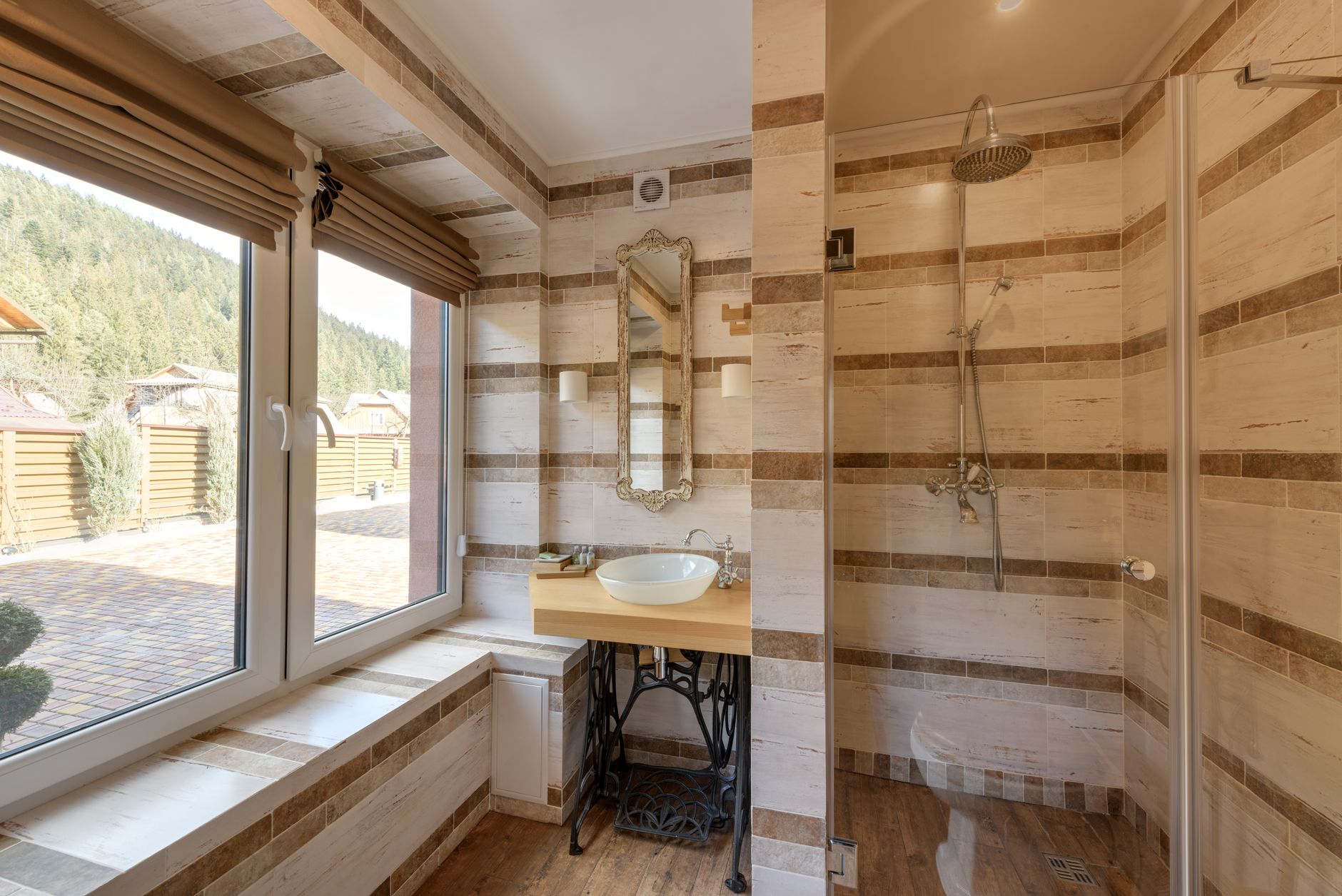 A bathroom with a shower and mirror lit by natural light