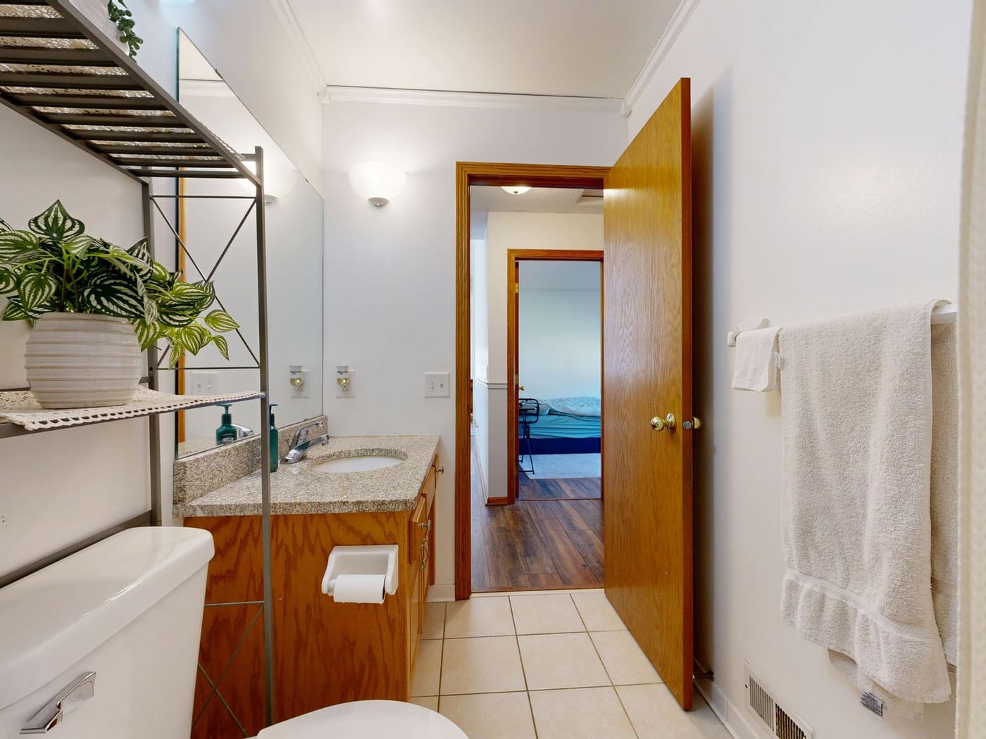Small bathroom with an oak vanity, a leafy plant on a shelf and a white towel