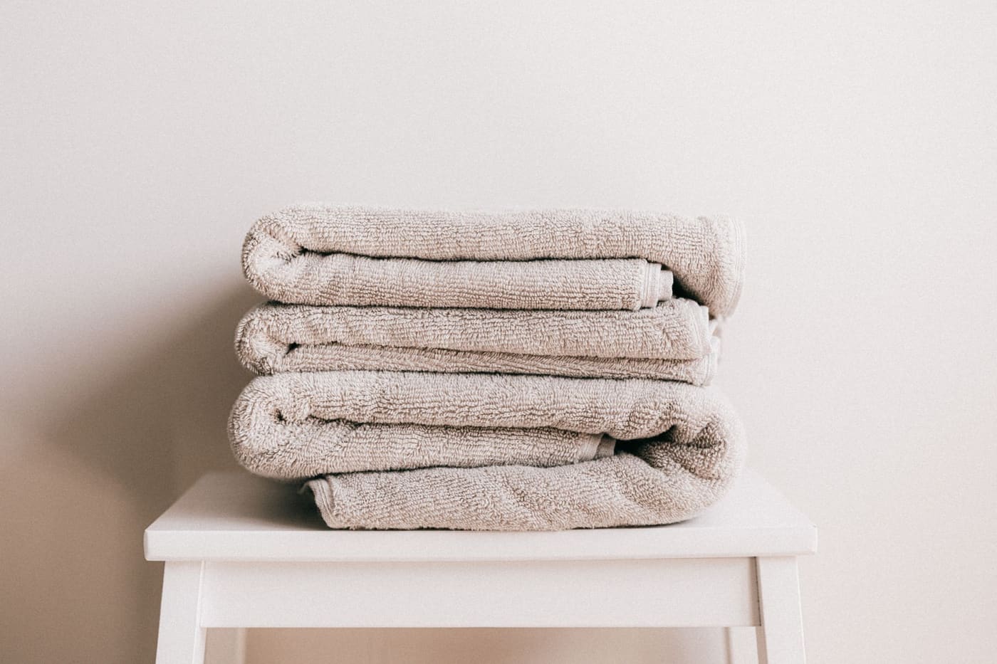Stack of folded beige towels on a small white stool