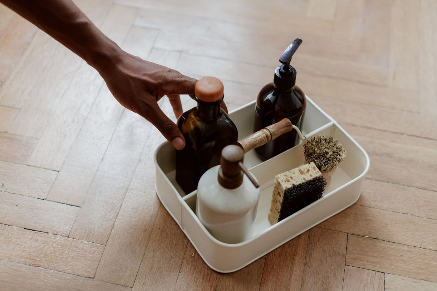 Hand lifting a tray holding cleaning bottles and brushes