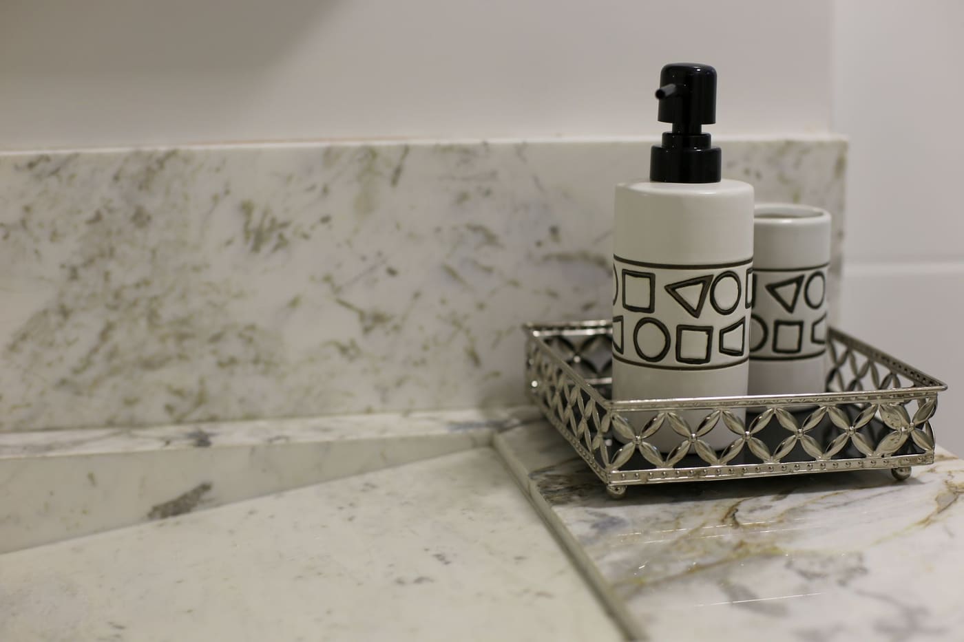 Pump bottle and a cup on a silver tray on a marble counter