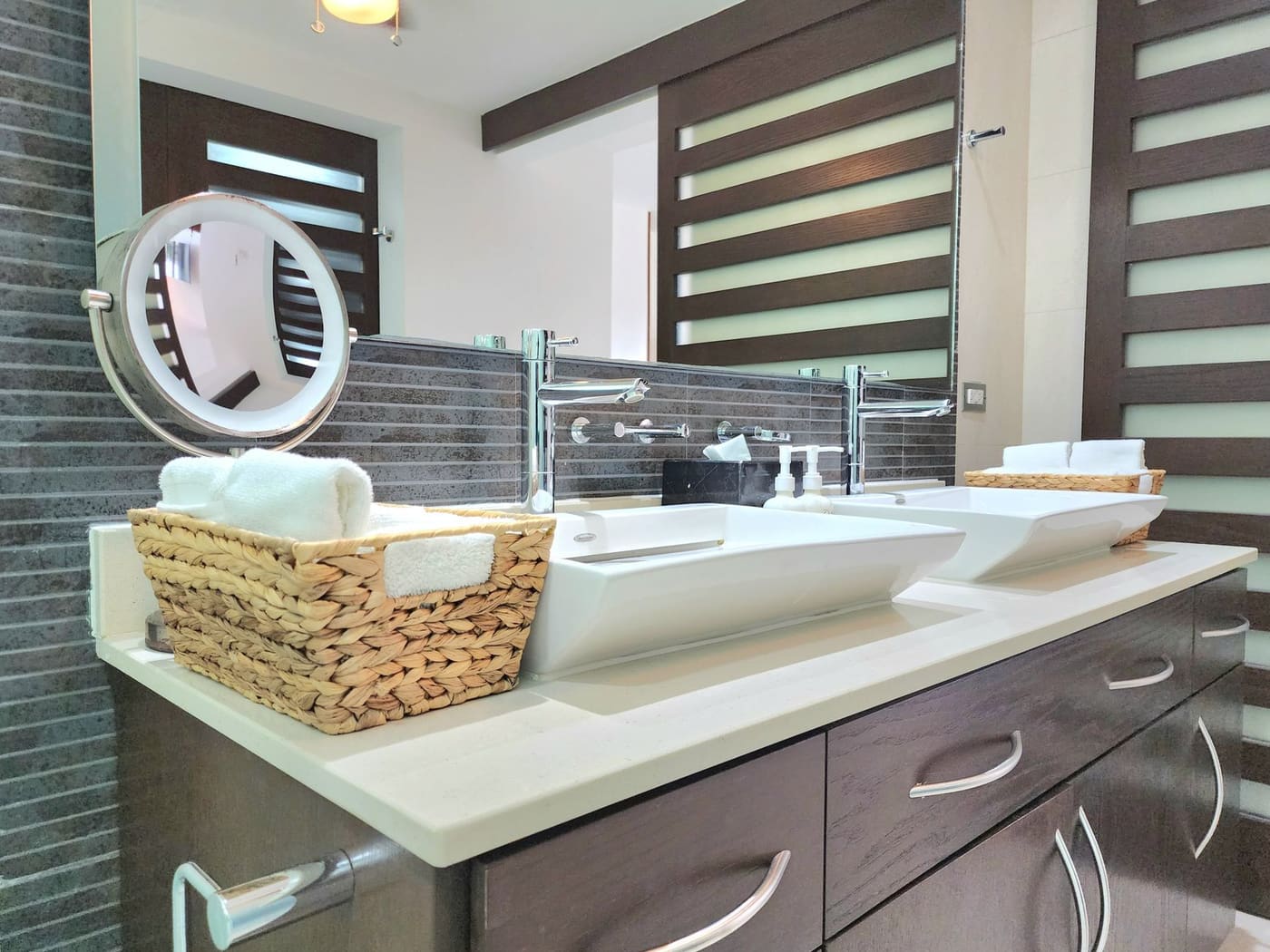 Wicker basket of rolled towels on a double vessel-sink vanity