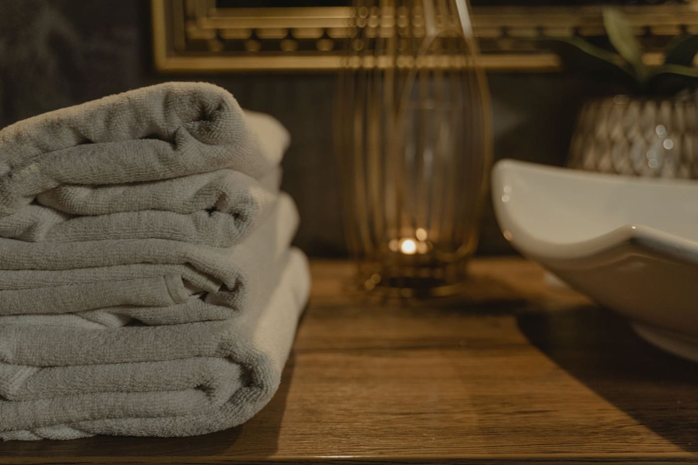 Stack of soft grey towels beside a small lit candle