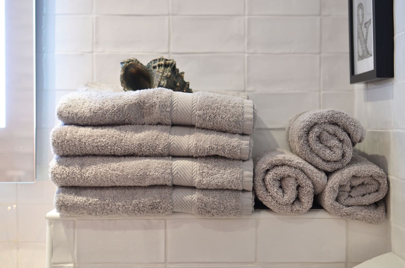 Soft grey towels stacked on a tile ledge