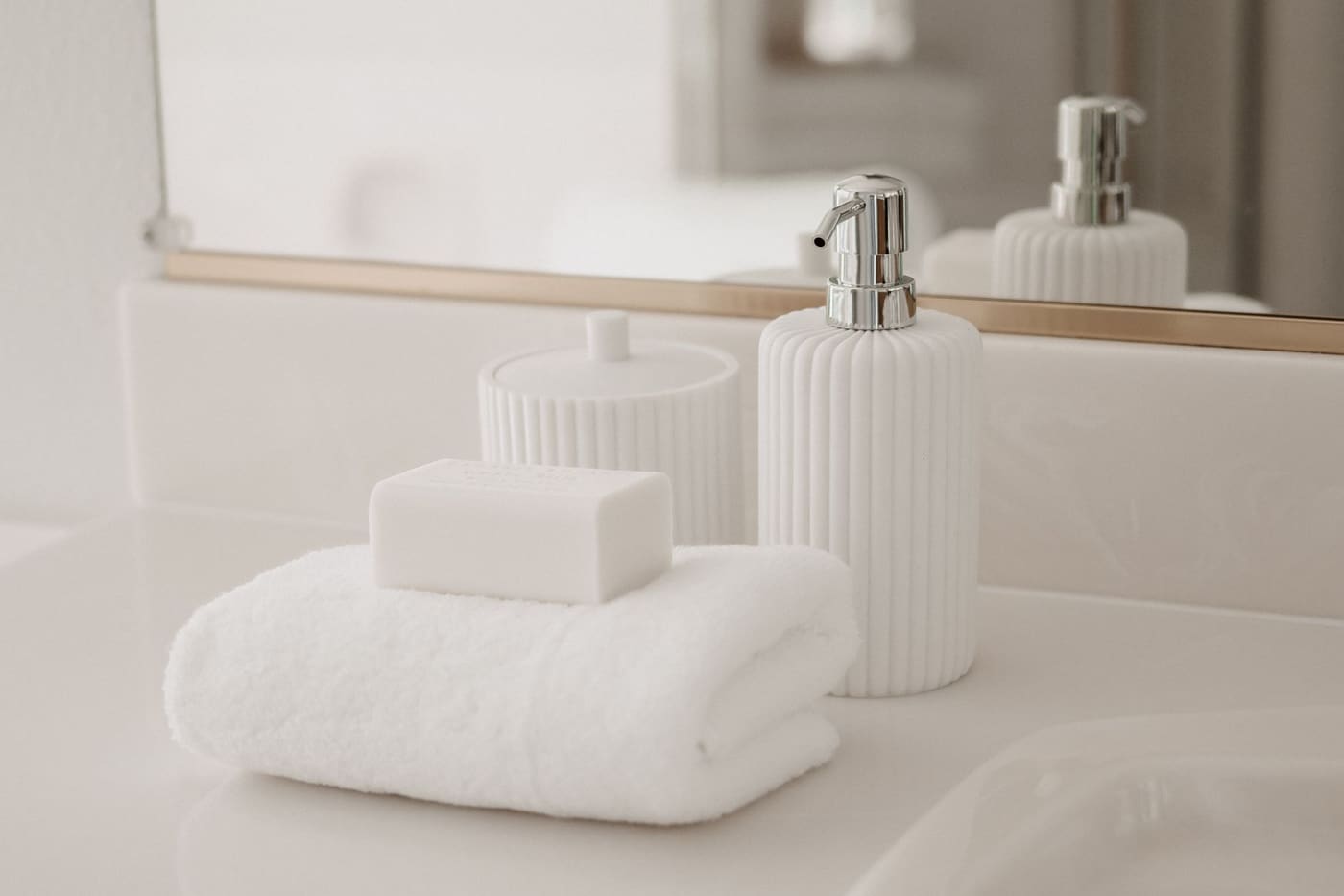 Folded white towel with a bar of soap and a soap dispenser on a bathroom counter