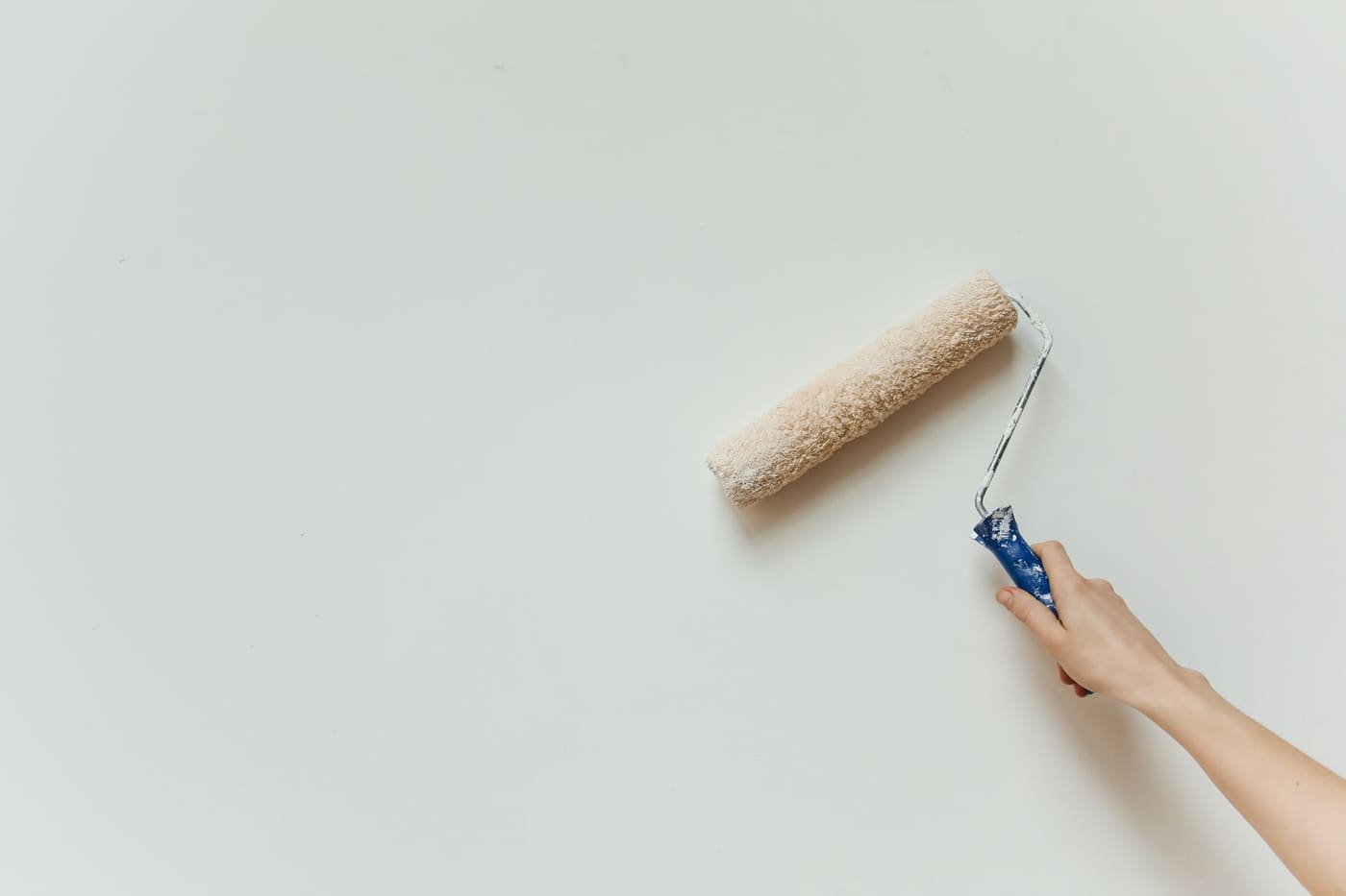 Hand painting a light wall with a paint roller