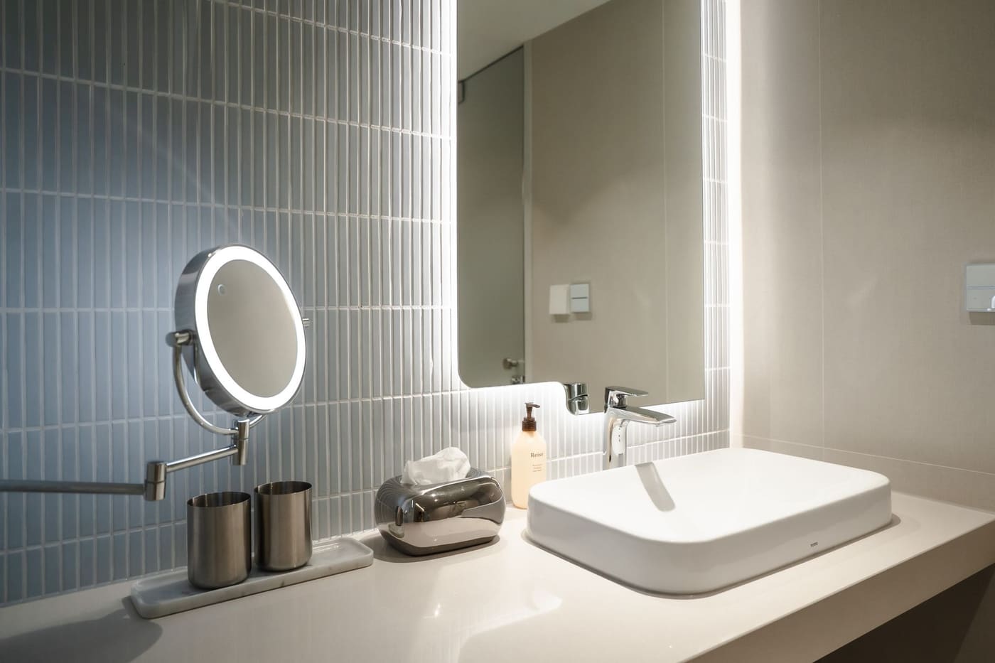 Small bathroom vanity with a lighted magnifying mirror on the wall