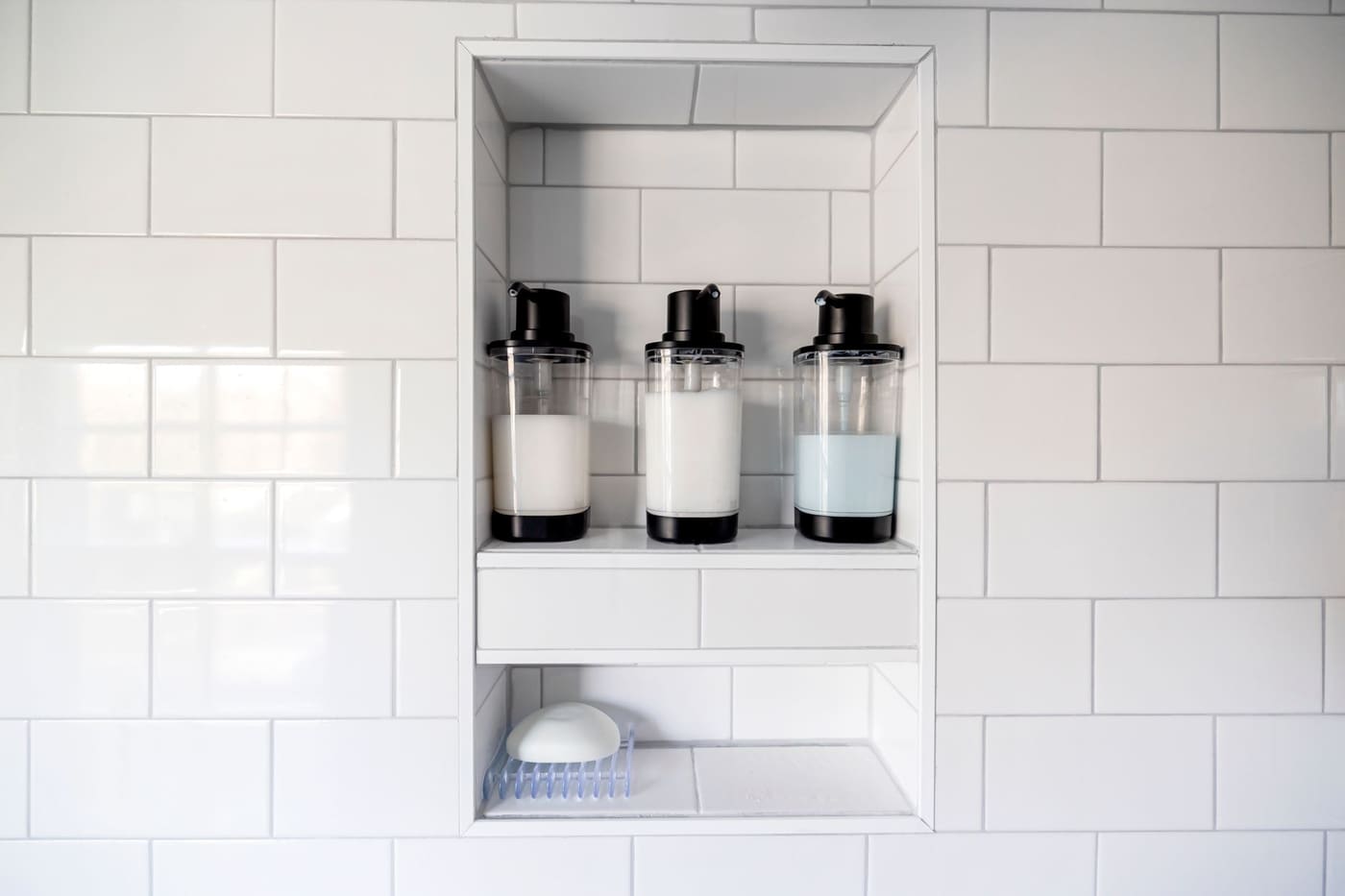 Soap dispensers on a tiled shower niche shelf
