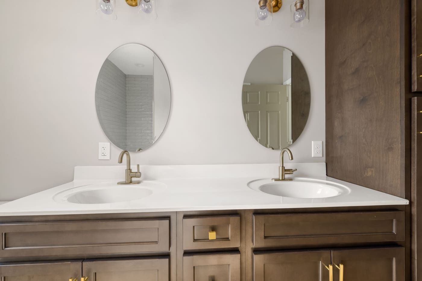 Two oval mirrors above a double vanity with two faucets