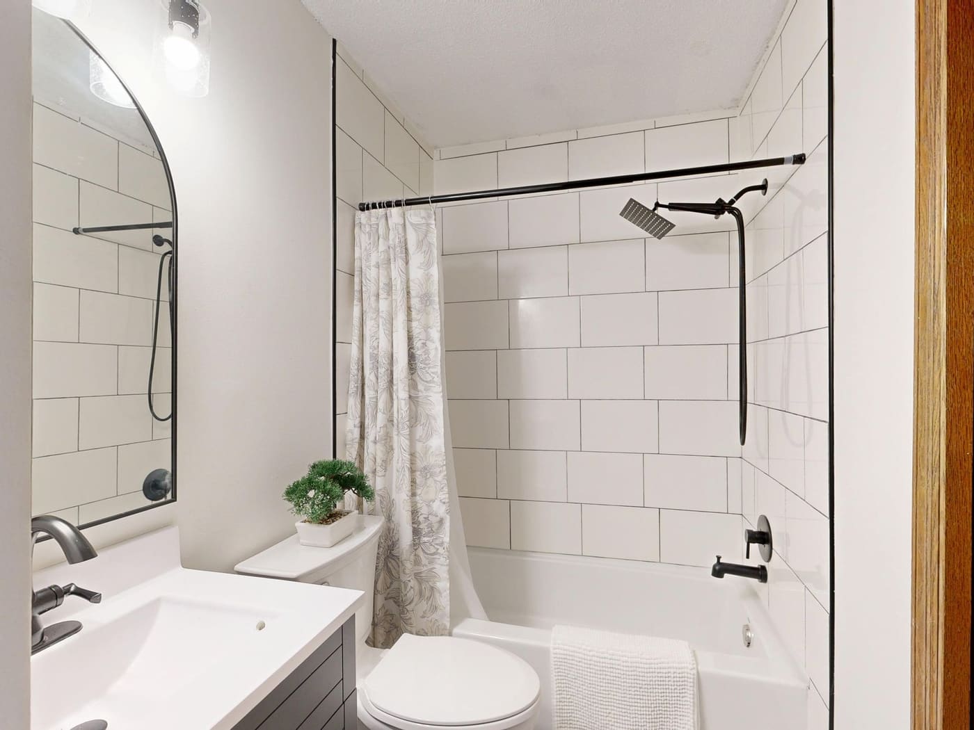 Patterned fabric shower curtain on a rod over a tiled tub with a showerhead