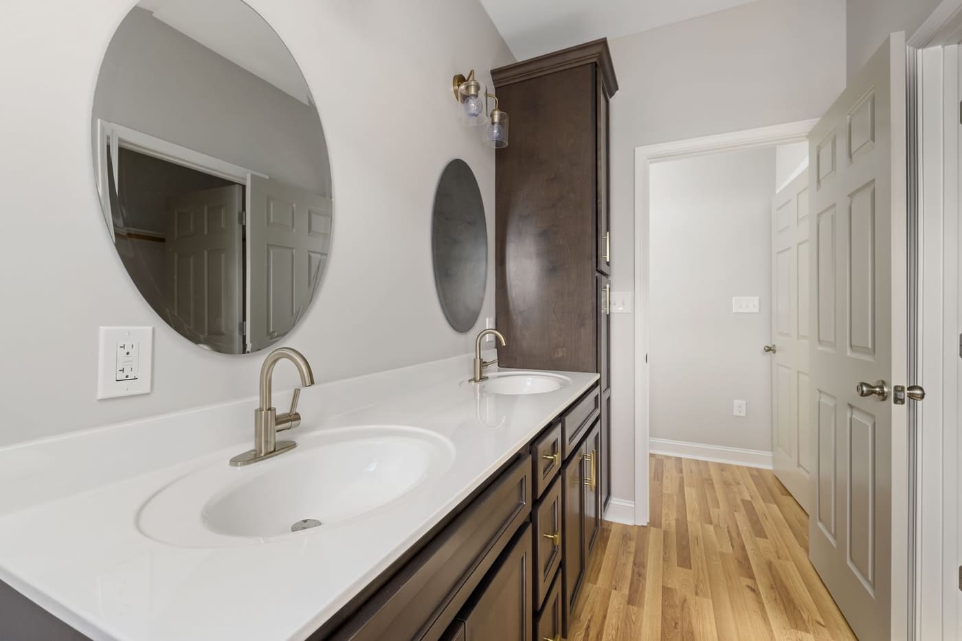 Two round black-framed mirrors above a double vanity with a vase of flowers between them