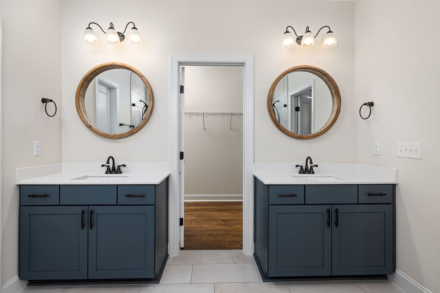 Two round mirrors over a double vanity with lit fixtures above