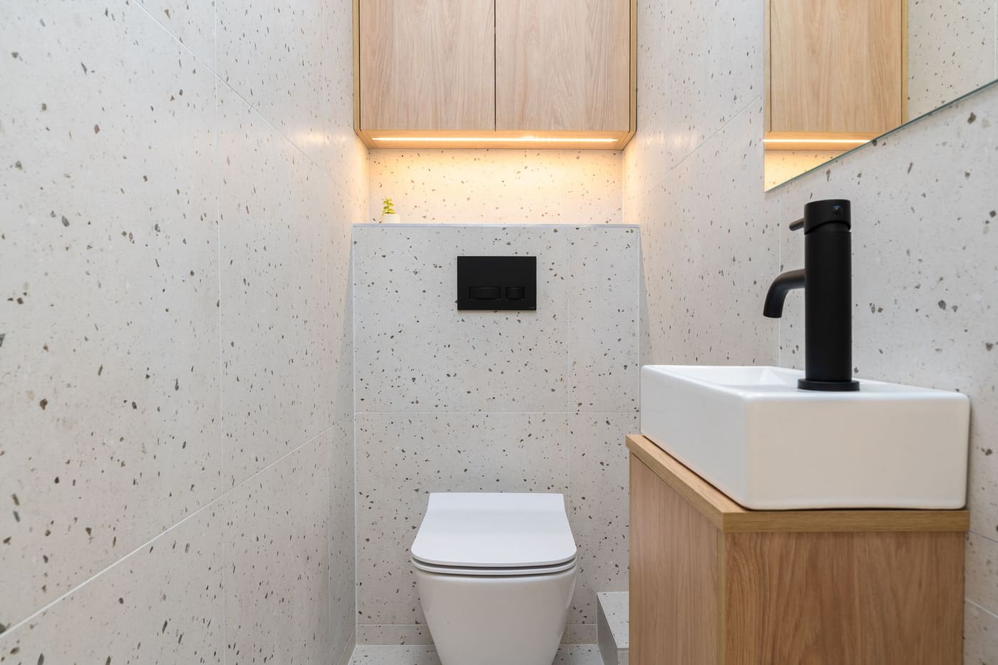 Small white-tiled bathroom with a floating wood vanity and black faucet