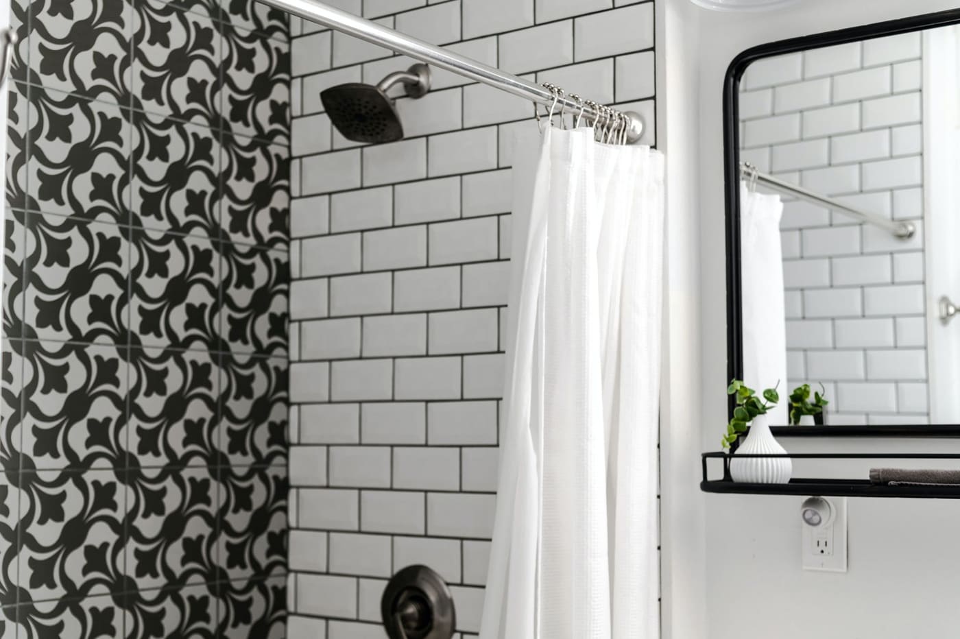 Bathroom with a plug-in night light below a shelf and mirror, next to a white shower curtain