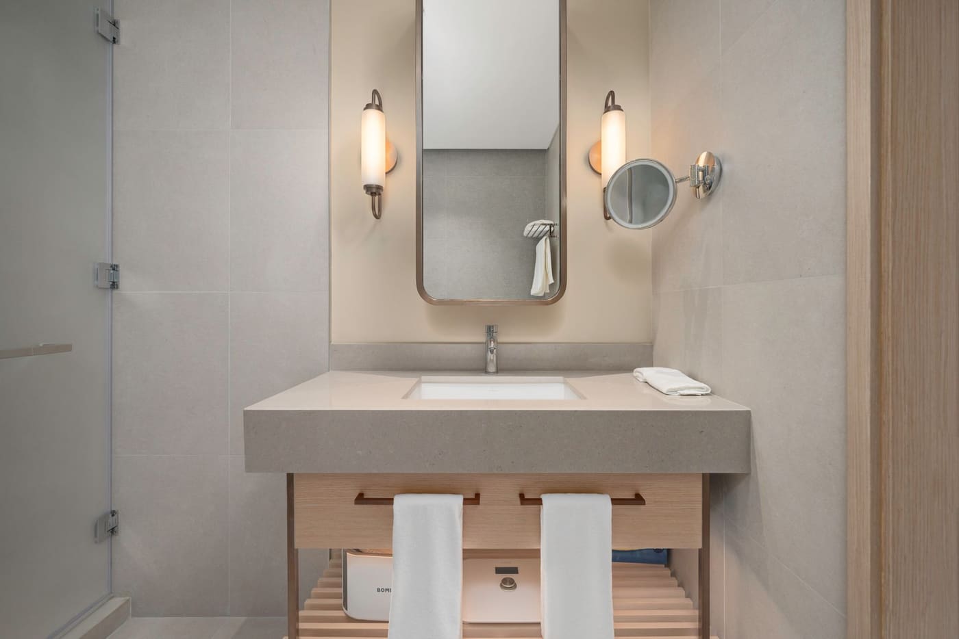 Bathroom vanity with soft lighting and a wall-mounted magnifying mirror