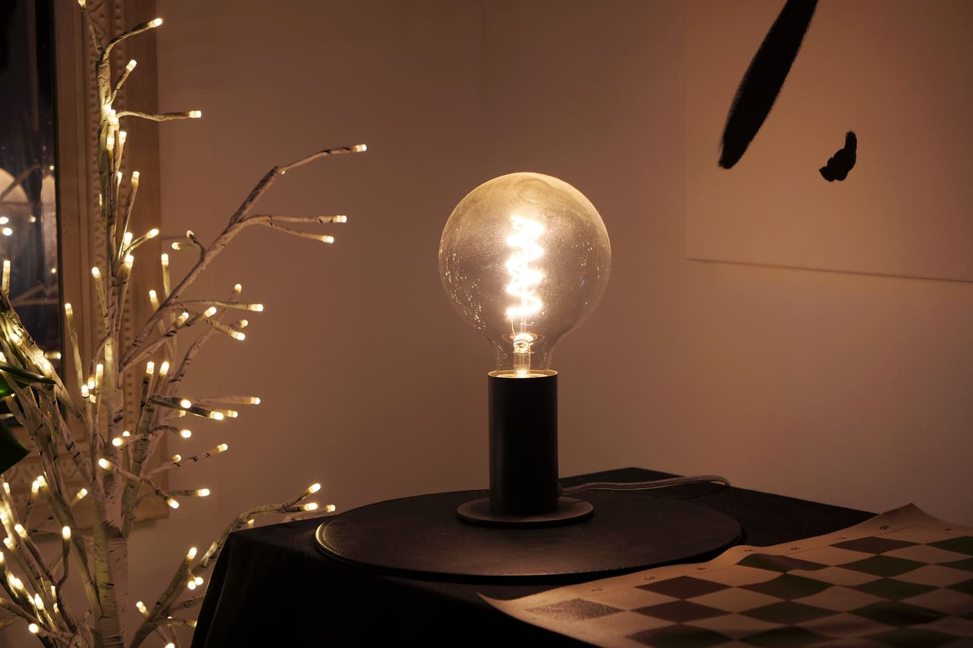 A warm-white LED bulb glowing on a small black lamp base
