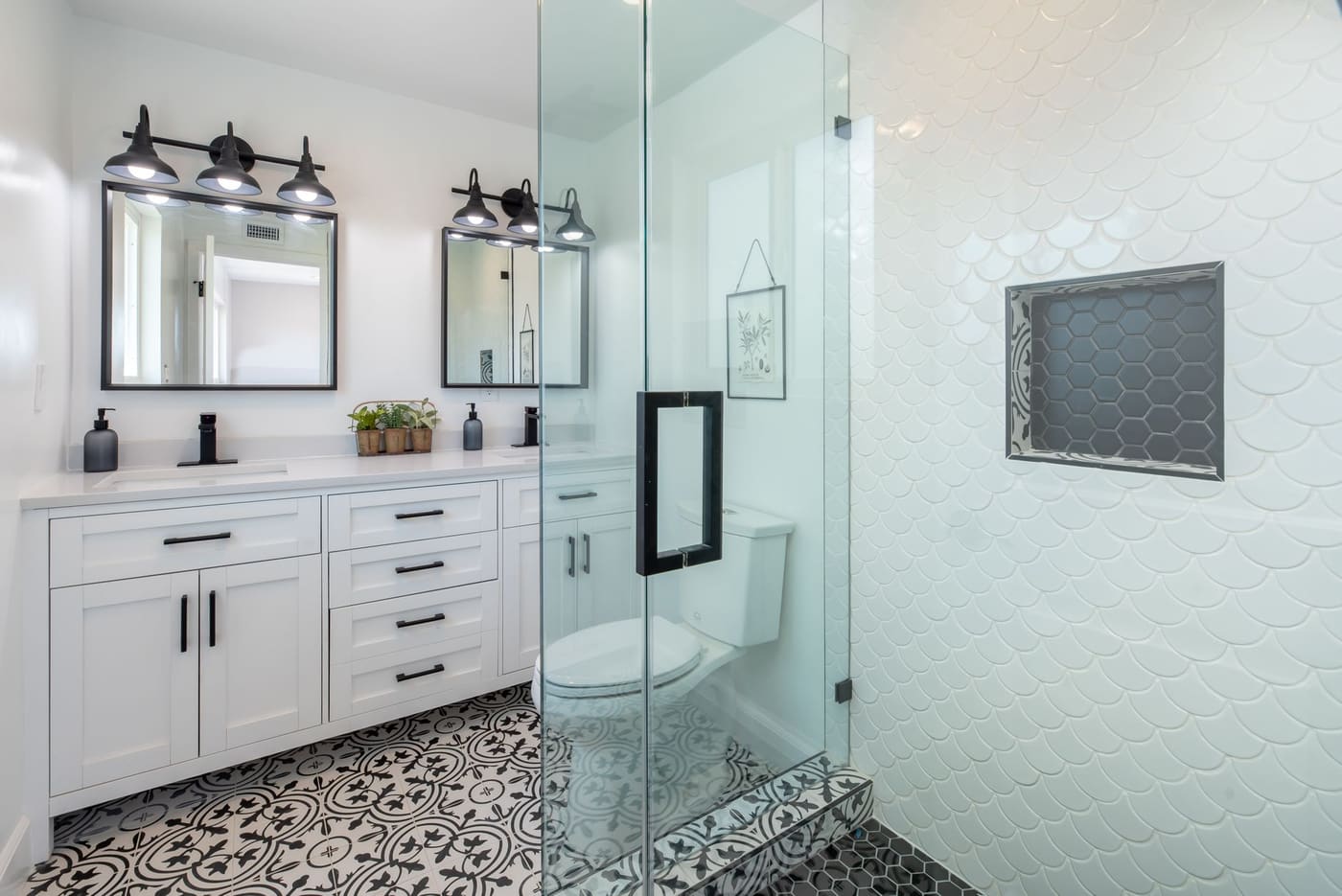 White bathroom with a glass shower and black-and-white patterned floor tile