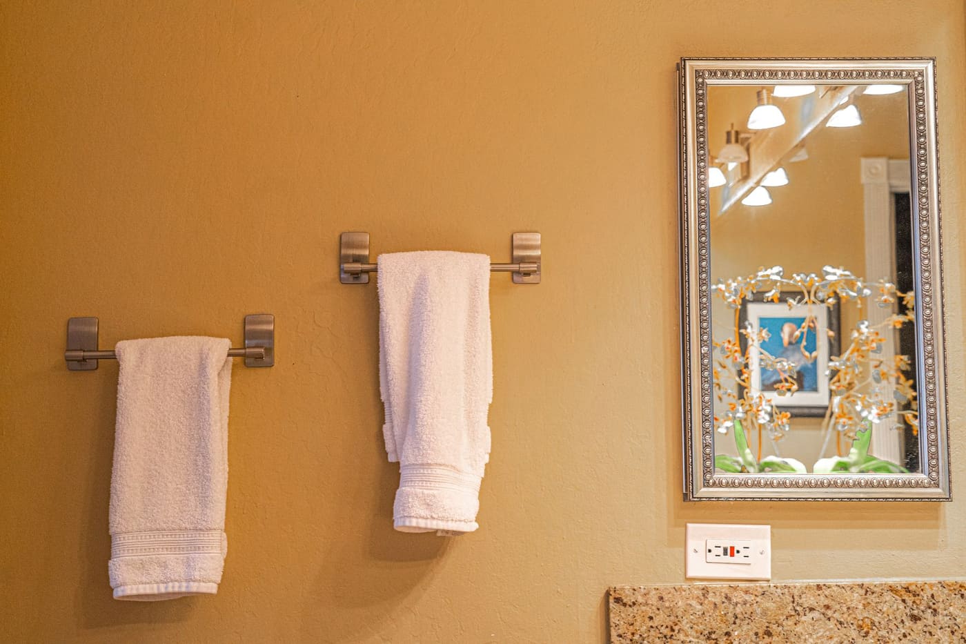 White towels hanging on bars beside a bathroom mirror