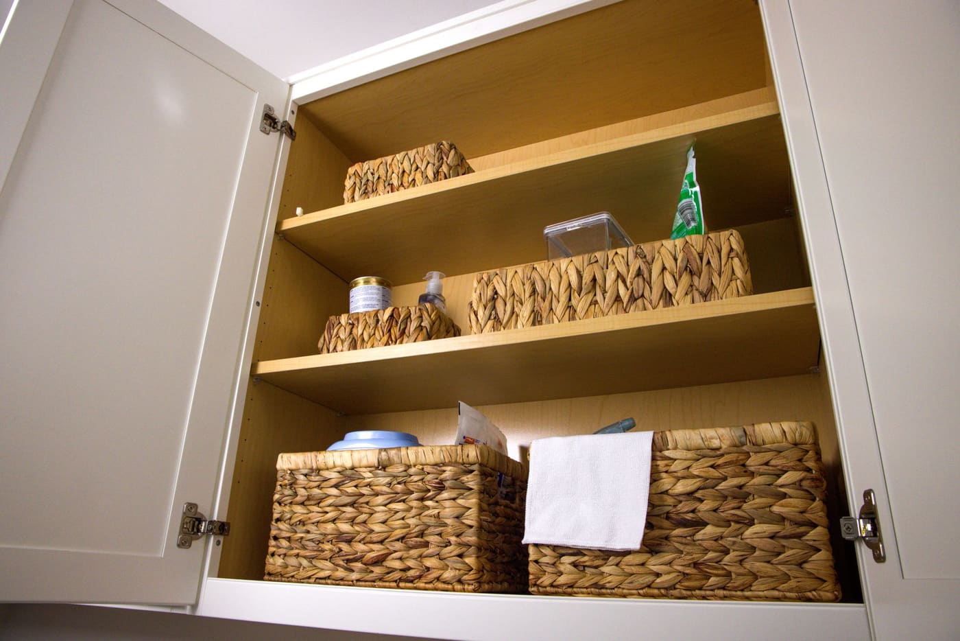 Cabinet shelves with wicker baskets and a folded towel