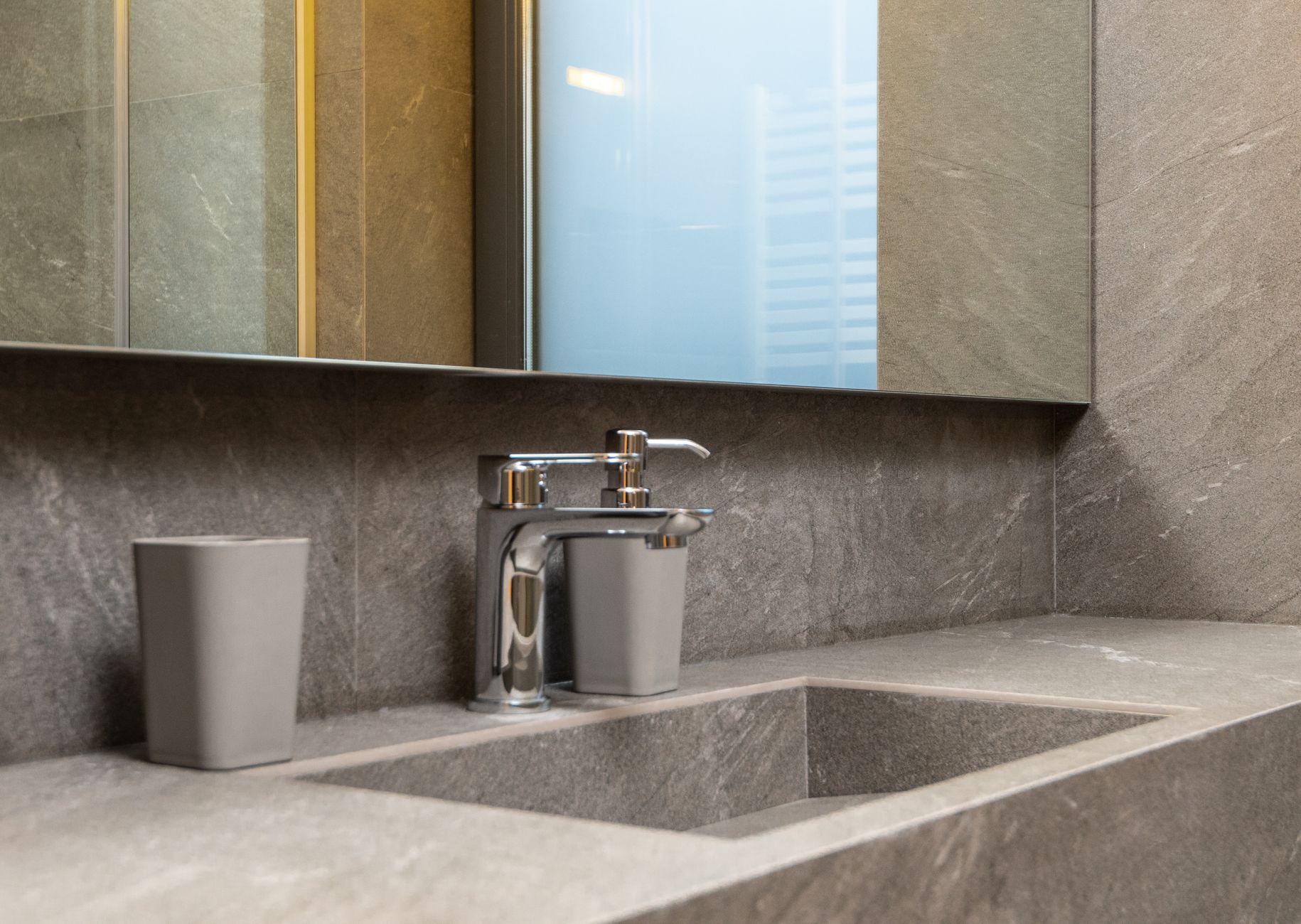 Chrome faucet and marble sink under a mirror in a modern bathroom